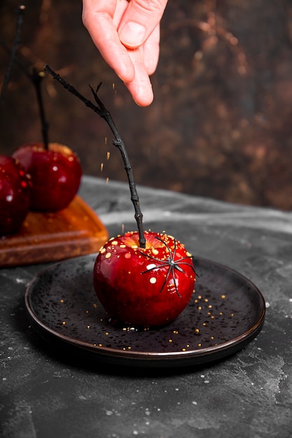 Cospargere una mela rossa nel caramello con decorazioni di zucchero un regalo originale per una tavola festiva di Halloween