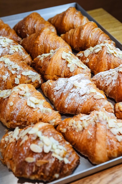 Cospargi i croissant finiti su una teglia con scaglie di mandorle e zucchero a velo