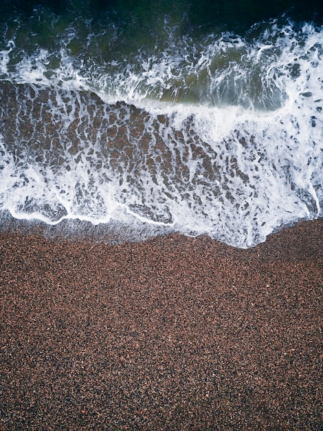 Costa con le onde come sfondo dalla vista dall'alto Sfondo di acqua blu dal drone Paesaggio marino estivo Concetto di vacanza di viaggio