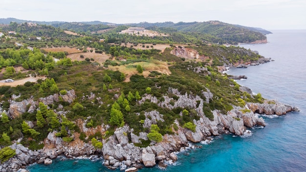 Costa del Mar Egeo della Grecia, scogliere rocciose, vegetazione e acqua blu. Vista dal drone
