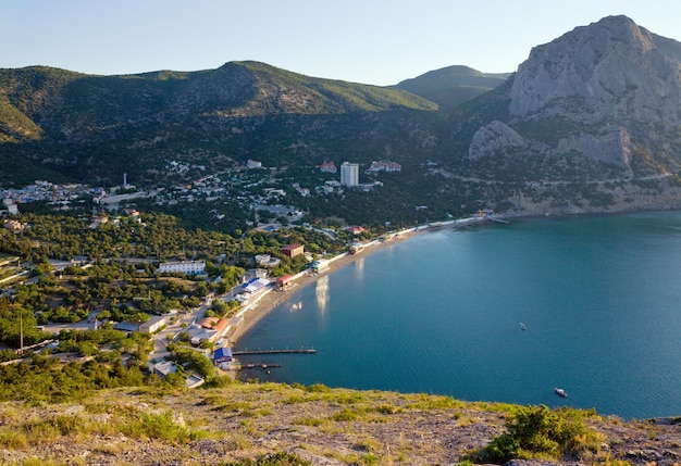 Costa della città "Novyj Svit" con riflessi del sole mattutino nella superficie dell'acqua del mare azzurro (Crimea, Ucraina)