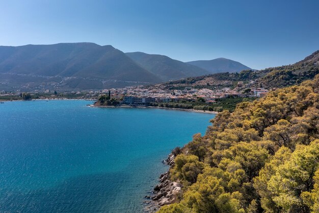 Costa mediterranea con roccia ricoperta da alberi piccola città e montagne Epidavros Grecia