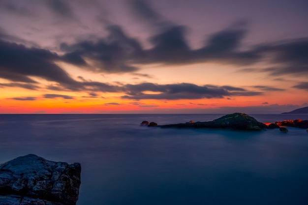 Costa rocciosa del mare. Tramonto colorato nel cielo con le nuvole