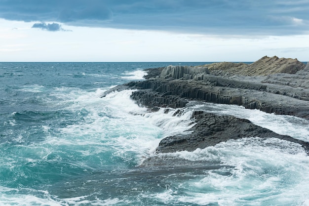 Costa rocciosa formata da basalto colonnare sullo sfondo di un mare tempestoso paesaggio costiero delle Isole Curili