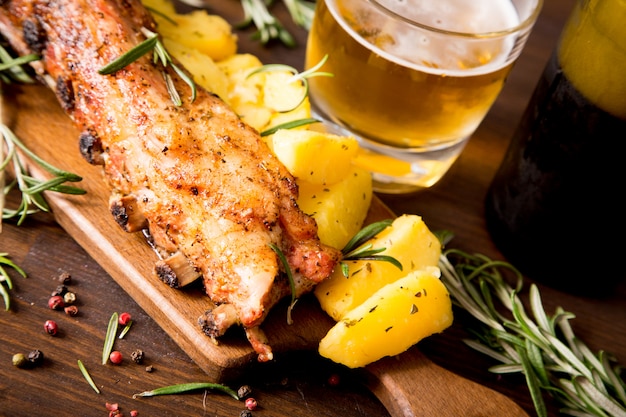 Costine di maiale al forno con patate, rosmarino e un bicchiere di birra