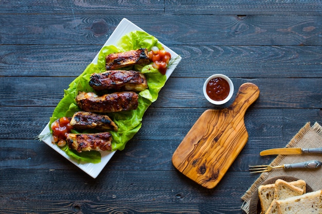Costine di maiale alla griglia barbecue con verdure su un tavolo di legno