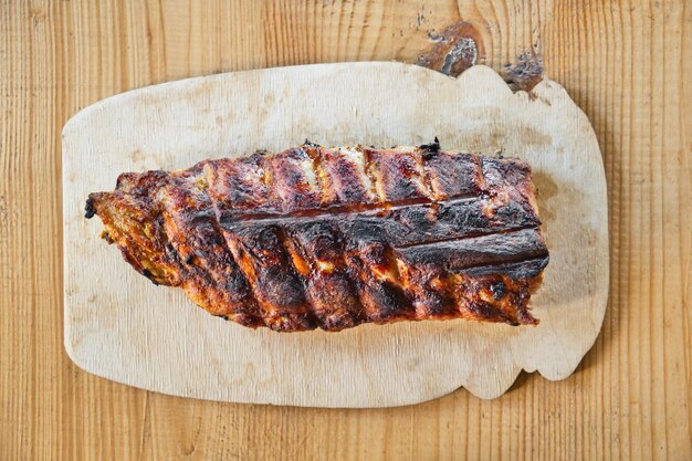 Costine di maiale alla griglia barbecue su tavola di legno su tavola di legno sullo sfondo. Vista dall'alto.