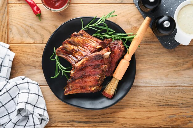 Costine di maiale alla griglia e affumicate con salsa barbecue su un vecchio tagliere di legno vintage su sfondo di un vecchio tavolo in legno Gustoso spuntino alla birra Concetto di cibo americano Vista dall'alto