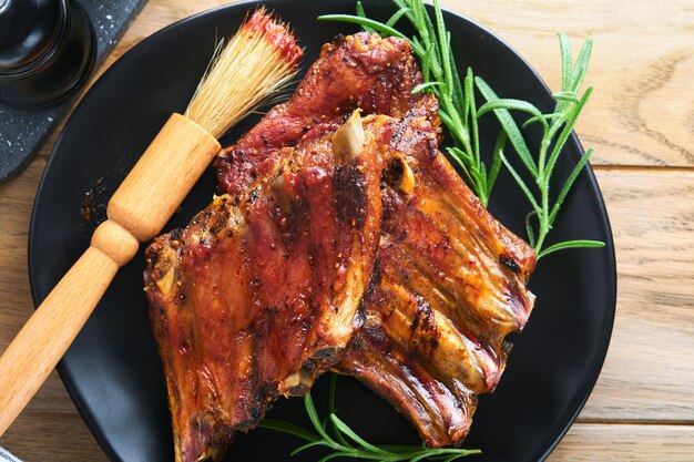 Costine di maiale alla griglia e affumicate con salsa barbecue su un vecchio tagliere di legno vintage su sfondo di un vecchio tavolo in legno Gustoso spuntino alla birra Concetto di cibo americano Vista dall'alto