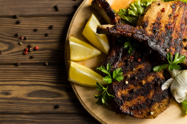 Costine di maiale fritte con limone, aglio e spezie. In un piatto, su un tavolo di legno.