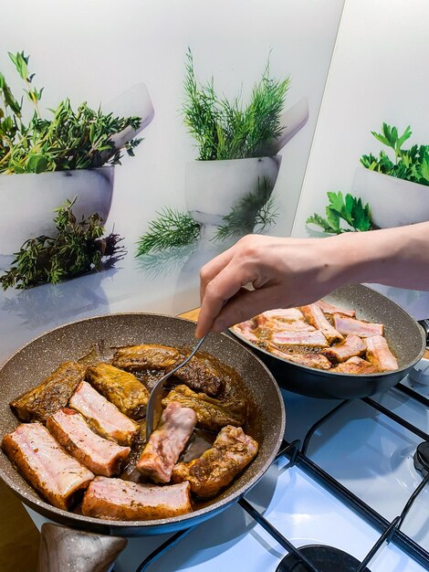 Costine di maiale fritte in padella grande sul fornello a gas nella cucina di casa