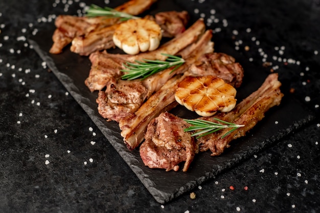 Costolette di agnello alla griglia con spezie e aglio su uno sfondo di pietra