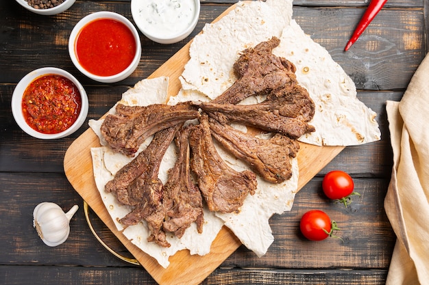 Costolette di agnello arrosto con salsa su pita su legno,