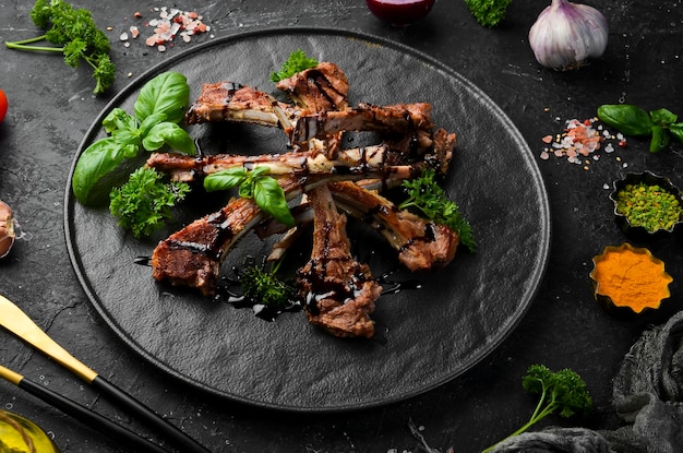 Costolette di agnello arrosto con spezie e aglio su un tavolo da cucina scuro Stile rustico Foto per il catalogo