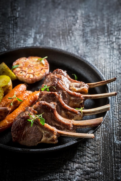 Costolette di agnello arrosto con verdure su fondo scuro