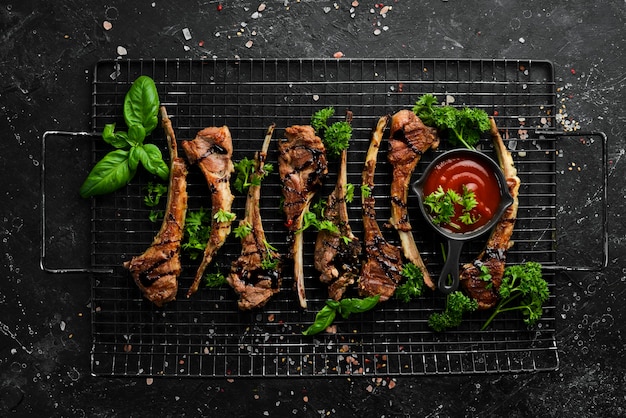 Costolette di agnello crude e condimenti alla griglia, da preparare per il barbecue. La carne. Vista dall'alto.