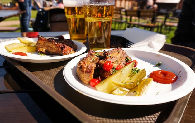 Costolette di maiale su un vassoio e cibo da festival del cibo di strada della birra leggera in una giornata di sole