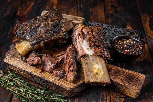 Costolette di manzo al barbecue con erbe aromatiche e mannaia. Fondo in legno scuro. Vista dall'alto.