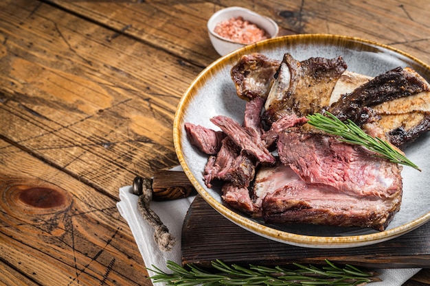 Costolette di manzo di vitello arrosto in piastra con rosmarino Sfondo in legno Vista dall'alto Spazio di copia