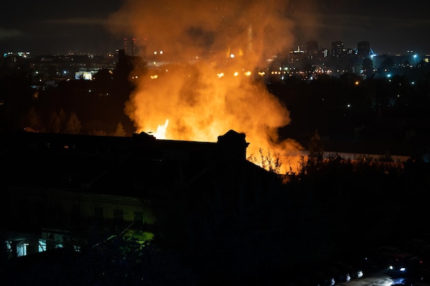 Costruire in fiamme di notte fiamme arancioni e fumo pesante sulla città