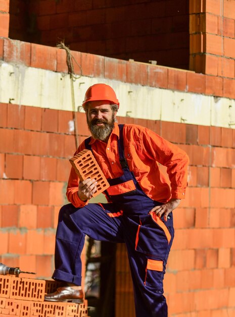 Costruisci il tuo futuro uomo barbuto felice tenere mattoni in muratura L'uomo prende il mattone dal mucchio Operaio edile maschio in possesso di mattoni Ragazzo riparatore duro costruire un nuovo livello di livello