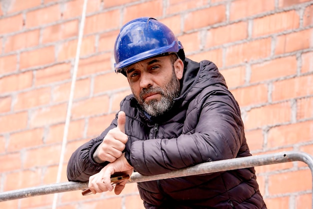 Costruttore con un casco protettivo in un cantiere di lavoro sullo sfondo di un muro di mattoni