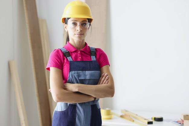 Costruttore di donna in casco protettivo in piedi in officina