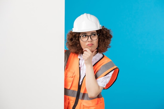 Costruttore femminile di pensiero di vista frontale in uniforme sulla parete blu