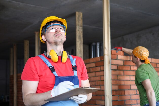 Costruttore in tuta e casco prende appunti su appunti.