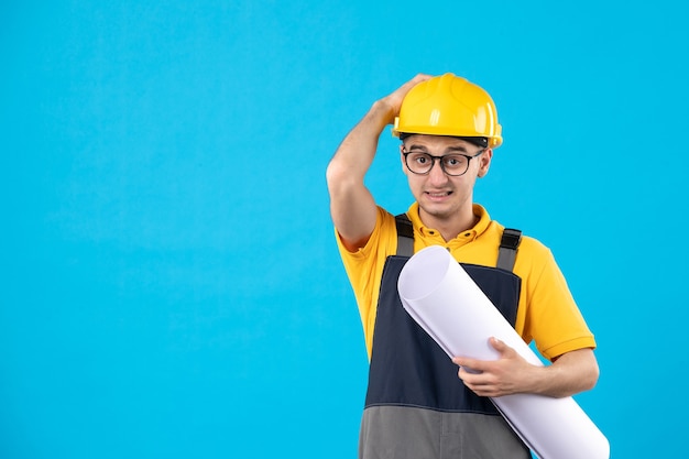 Costruttore maschio di vista frontale in uniforme gialla e casco sull'azzurro