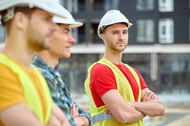 Costruttore serio in un giubbotto di sicurezza accompagnato dai suoi colleghi