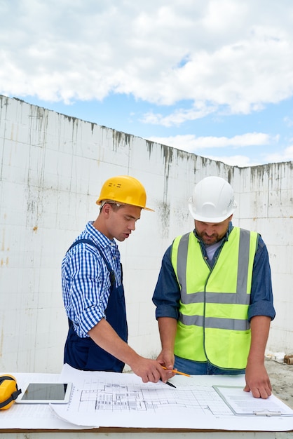 Costruttori che esaminano le planimetrie sul cantiere