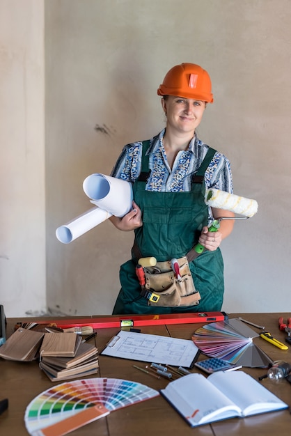 Costruttrice di donna con progetti in rotoli e tavolo da lavoro