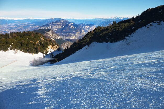 Costruzione della neve sulla pista sciista vicino a un cannone della neve che fa la neve nella stazione sciistica di montagna e nella stagione invernale