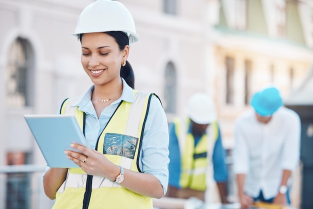 Costruzione di edifici e tablet con una donna architetto che lavora in città in un cantiere con il suo team sullo sfondo Ingegnere designer e architettura con una giovane donna al lavoro online