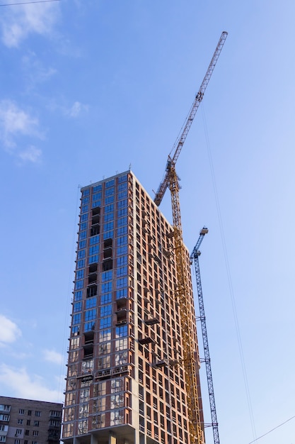 Costruzione di un grattacielo, gru da cantiere. Cielo blu.