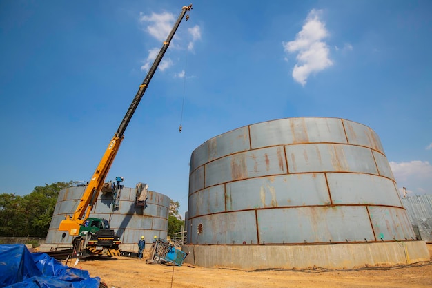 Costruzione di una gru a torre dell'olio, grandi serbatoi dell'olio sullo sfondo.