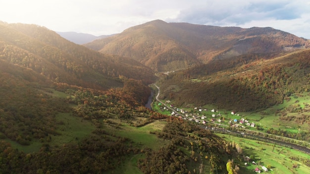 Costruzioni del paesino di montagna al fiume contro le colline marrone