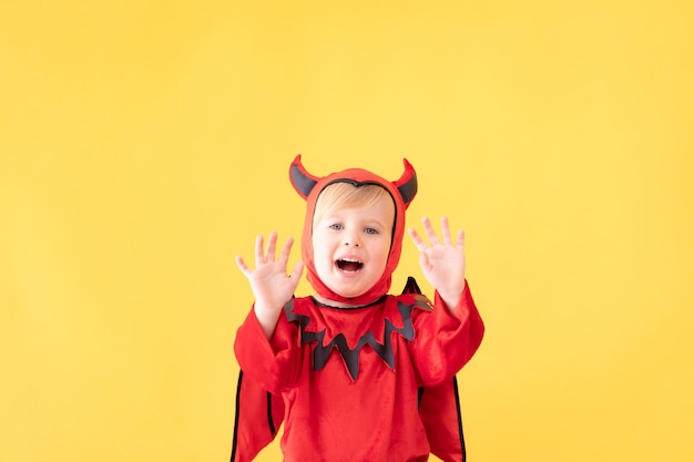 Costume da diavolo vestito bambino divertente contro la superficie gialla