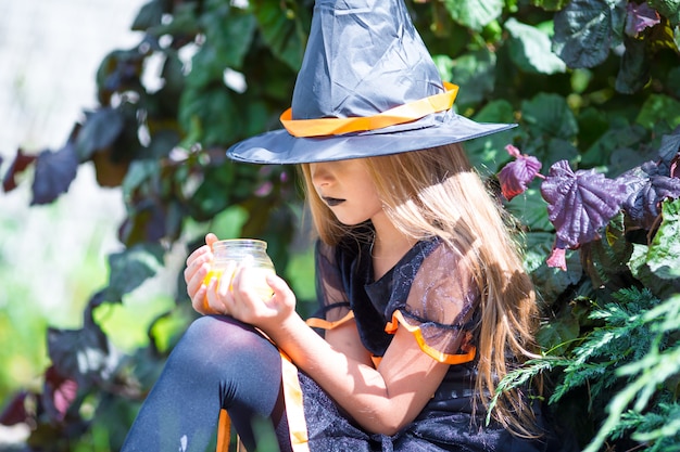 Costume da portare della strega della bambina adorabile con la scopa su Halloween all'aperto