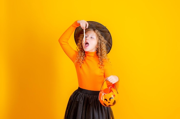 costume da strega per ragazza adolescente su sfondo giallo con vermi di marmellata di zucca confent halloween