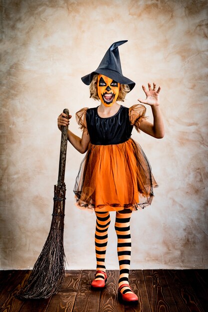 Costume da strega vestito da bambino divertente. Il bambino ha dipinto una zucca terribile. Concetto di vacanza autunnale di Halloween