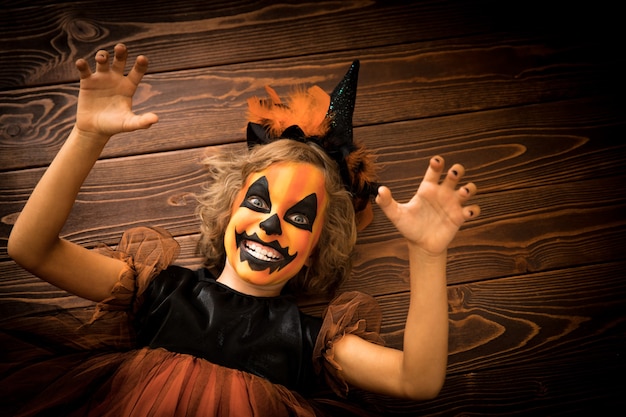 Costume da strega vestito da bambino divertente. Il bambino ha dipinto una zucca terribile. Concetto di vacanza autunnale di Halloween