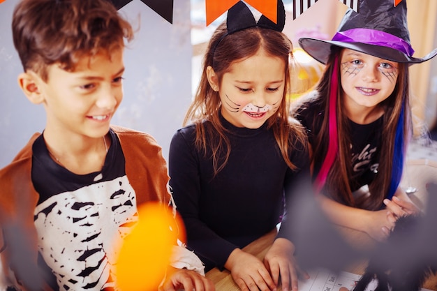 Costumi all'asilo. Tre bambini si sentono intrattenuti mentre indossano costumi di Halloween all'asilo