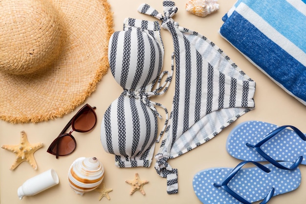 Costumi da bagno donna e accessori da spiaggia vista dall'alto piatta su sfondo colorato Concetto di viaggio estivo bikini costume da bagno cappello di paglia e conchiglie Spazio copia Vista dall'alto