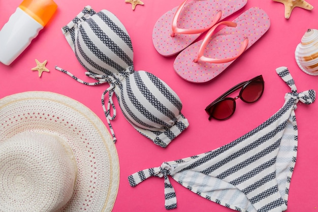 Costumi da bagno donna e accessori da spiaggia vista dall'alto piatta su sfondo colorato Concetto di viaggio estivo bikini costume da bagno cappello di paglia e conchiglie Spazio copia Vista dall'alto