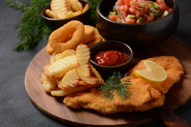 Cotoletta di carne e patate fritte con anelli di cipolla Insalata di verdure fritte