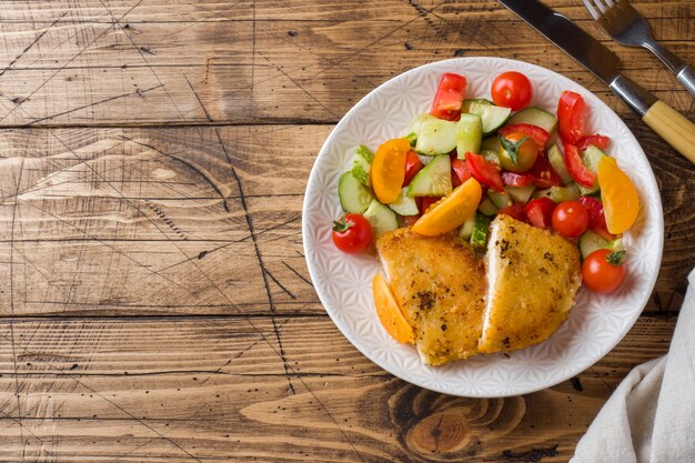 Cotoletta di pollo e insalata di cetrioli con pomodori