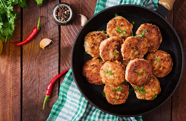 Cotolette deliziose succose della carne in pentola su una tavola di legno. Vista dall'alto