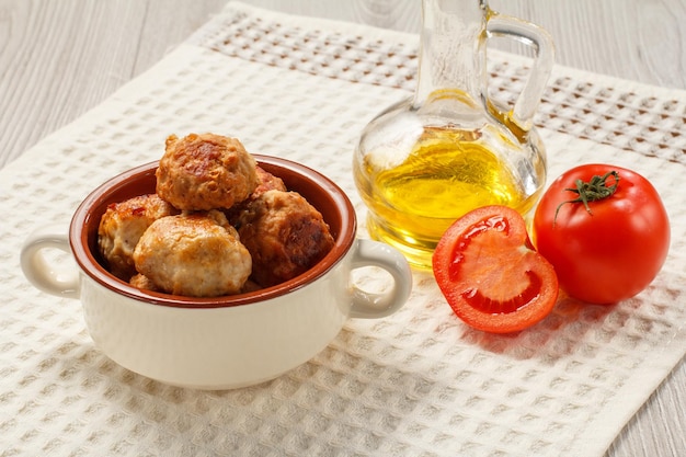 Cotolette di carne fritte in zuppiera di ceramica pomodori e olio di semi di girasole